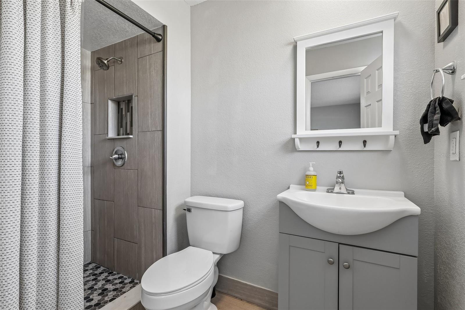 The primary bathroom has an updated stand-up shower, vanity, and decorative mirror