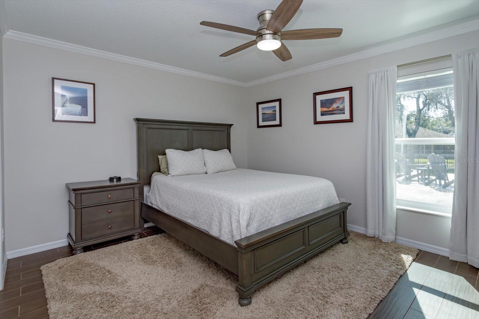 Freshly painted bedroom 2 features new fan, new blinds and wood look tile floors