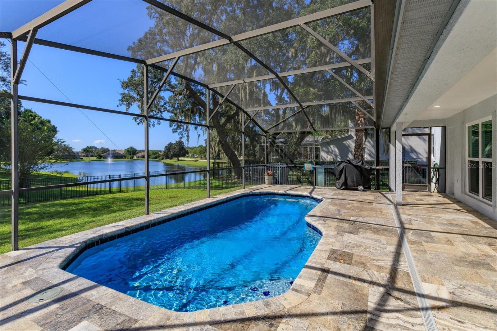 Freshly sealed Travertine pavers surround the screen enclosed pool