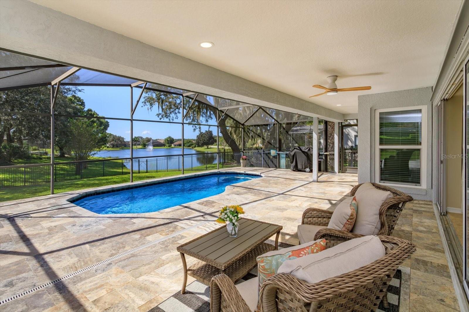 Travertine pavers on the covered porch and pool with sunset and water views
