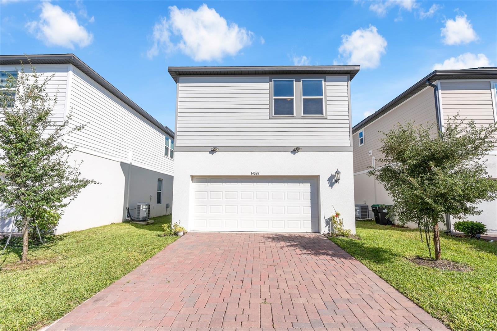 Rear exterior with two-car garage and paver driveway.