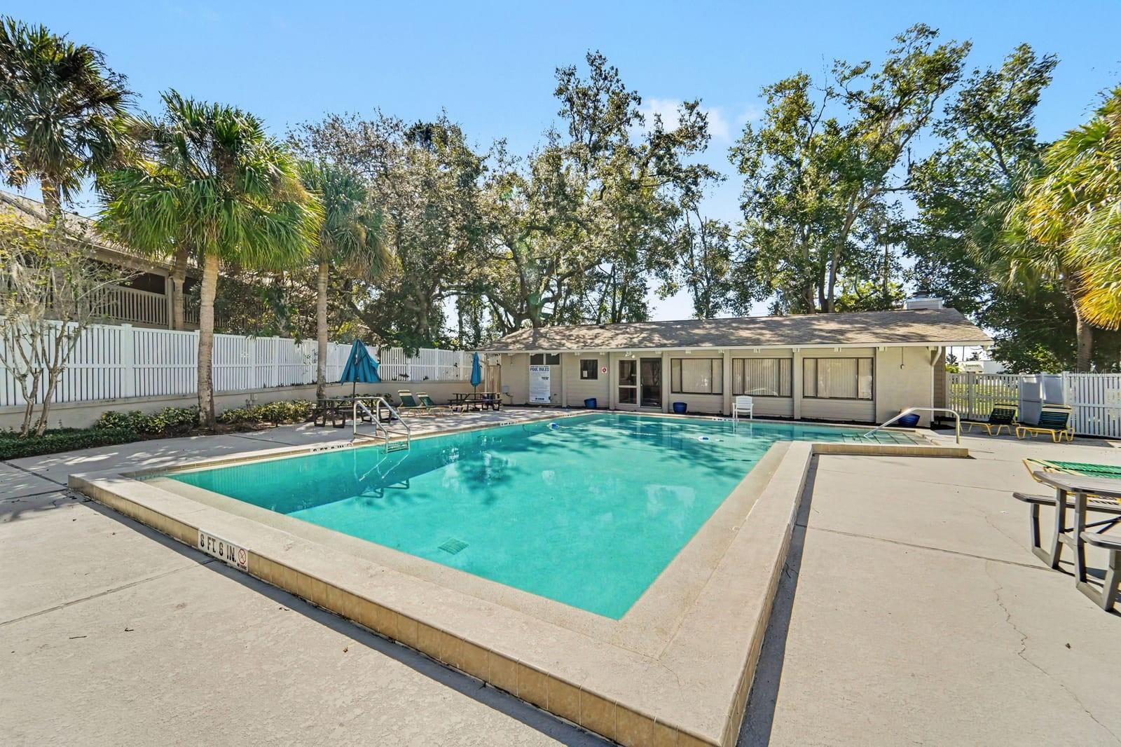 Resort-Style Community Pool Surrounded by Mature Trees and Lounging Area