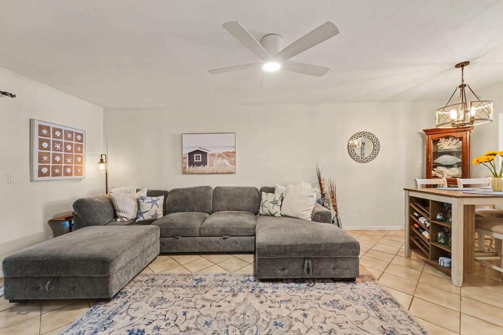 Open Living Room with Gray Sectional, Ceiling Fan, and Decorative Accents Open Living Room with Gray Sectional, Ceiling Fan, and Decorative Accents