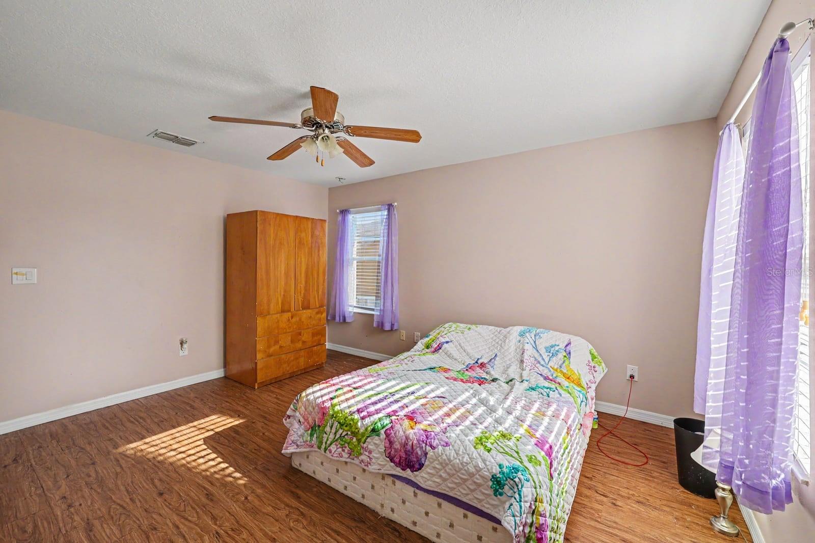 Spacious Bedroom with Wood Storage, Multiple Windows & Fan