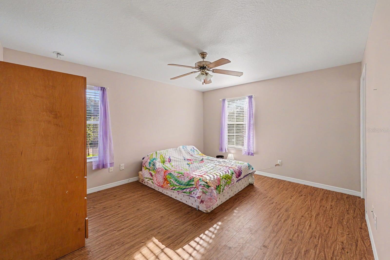 Large Bedroom with Multiple Windows, Wood Floors & Ceiling Fan