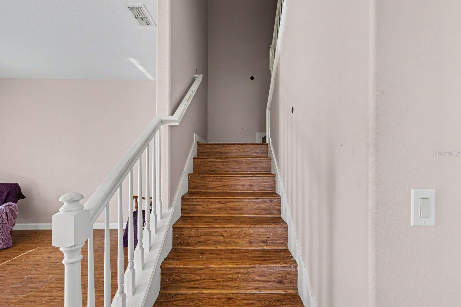 Staircase With White Rails & Wood Steps Connects Upper & Lower Levels