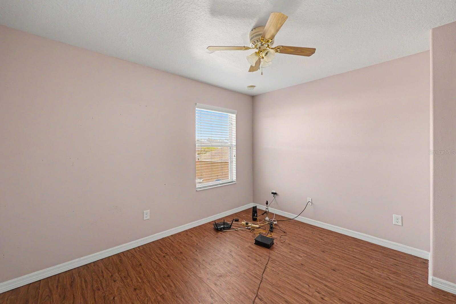 Spacious Bedroom with Wood Flooring, Large Window & Ceiling Fan