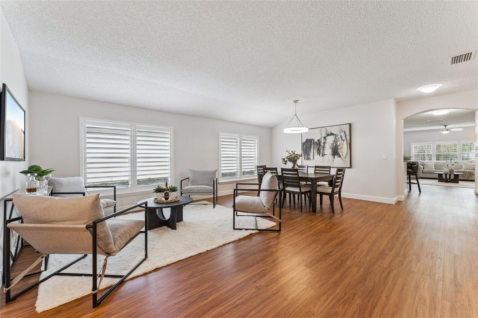 View of the Living & Dining Room areas w/ Plantation style shutters & a laminate floor