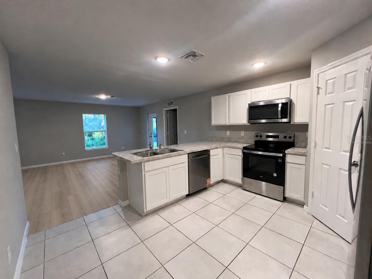 Kitchen and living area virtually staged: planned laminate flooring. Kitchen and living area virtually staged: planned laminate flooring.