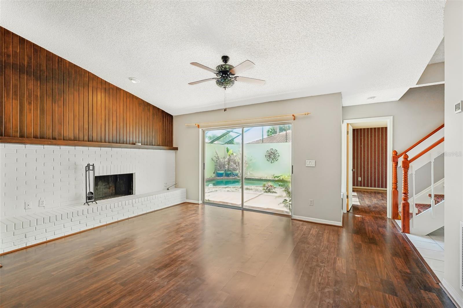 spacious living room with a wood-burning fireplace and laminate floors.