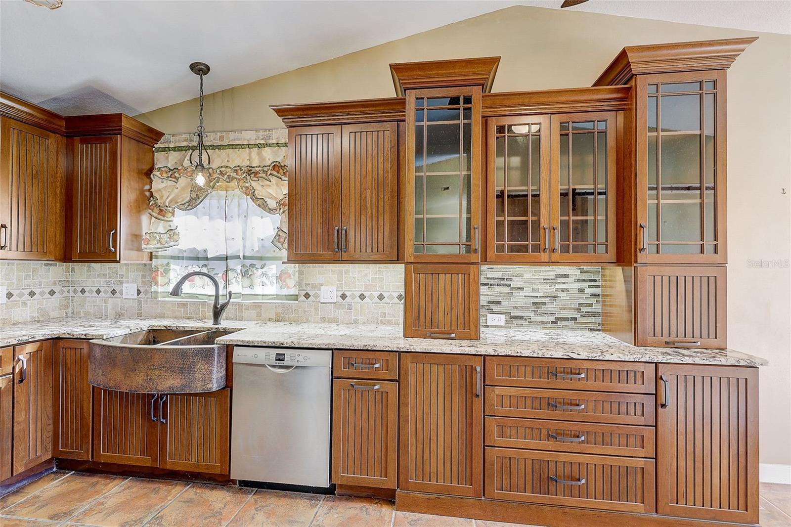 The custom-renovated kitchen, completed in 2021, is a standout feature, offering custom cabinetry with soft-close doors and drawers, polished granite countertops with natural edges, a custom tile backsplash, a copper undermount sink, and a touch-operated faucet with an integrated pot-filler feature. Additional details include a solid-wood barn door pantry, a built-in cabinet with antique glass doors and interior lighting, under-cabinet lighting, and quality appliances, including a French-door refrigerator, extra-quiet Bosch dishwasher, microwave installed in the lower cabinetry, and LG double oven, complemented by a full-size copper overhead range exhaust hood.