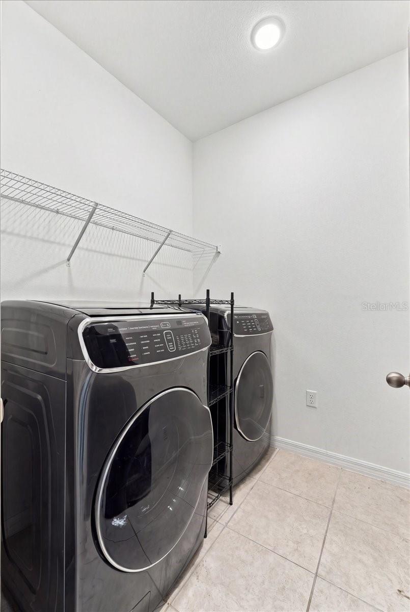 Dedicated indoor laundry room featuring convenient shelving and space for a full-size washer and dryer.