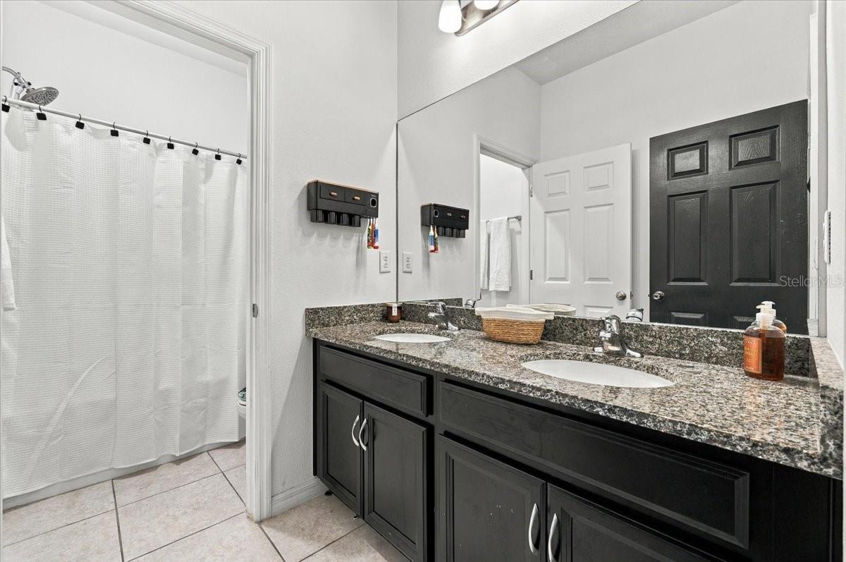 Full secondary bathroom featuring a double-sink vanity, generous countertop space, and a tub/shower combination. Full secondary bathroom featuring a double-sink vanity, generous countertop space, and a tub/shower combination.