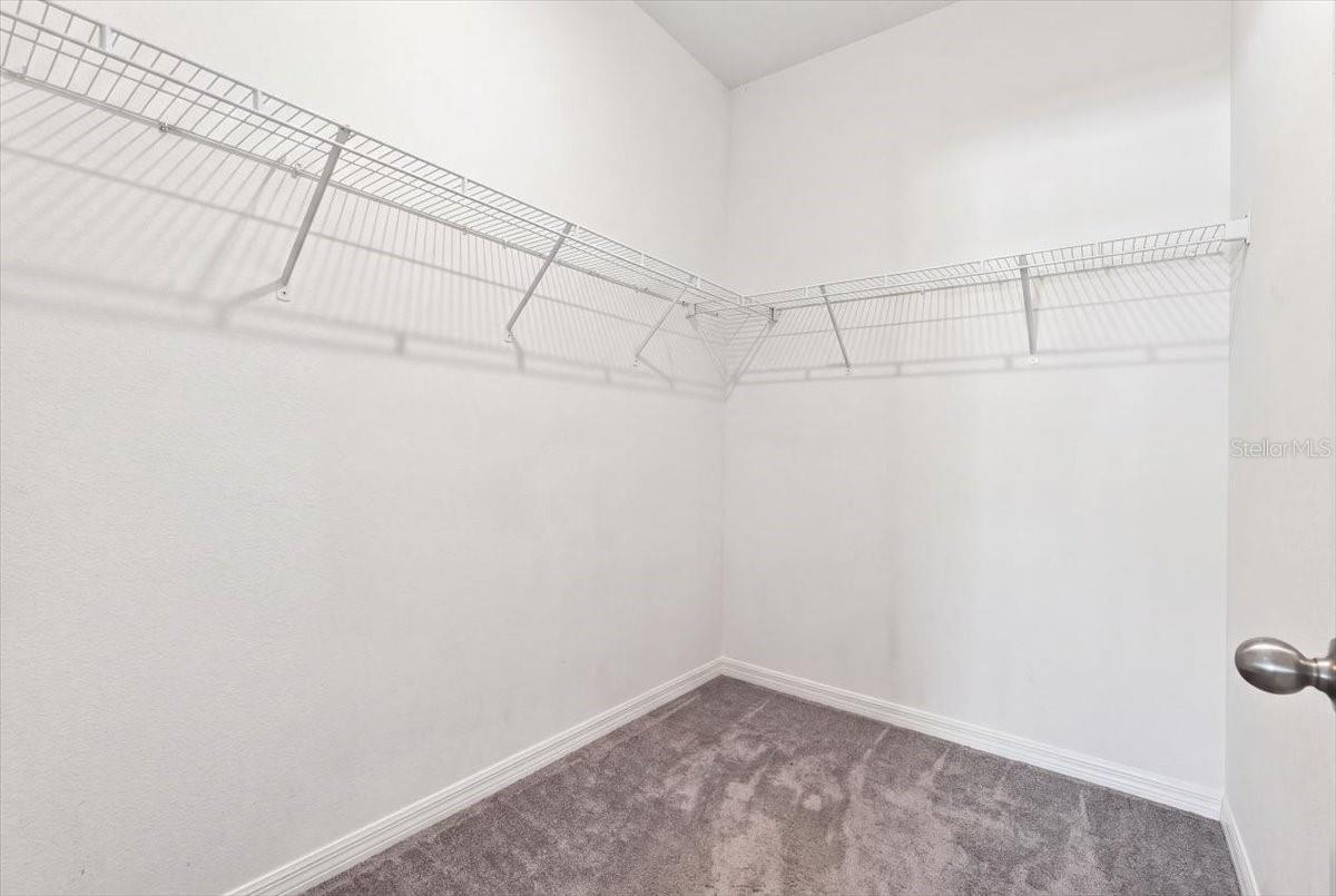 Spacious primary bedroom walk-in closet featuring ample shelving and hanging space for storage and organization. Spacious primary bedroom walk-in closet featuring ample shelving and hanging space for storage and organization.