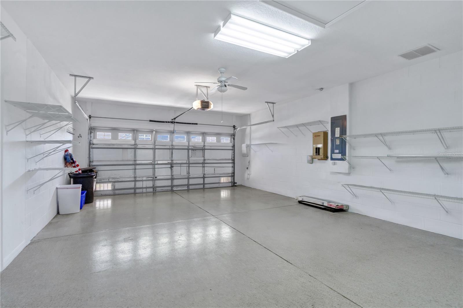 Spacious attached two-car garage with built-in storage shelving and room for vehicles and essentials.