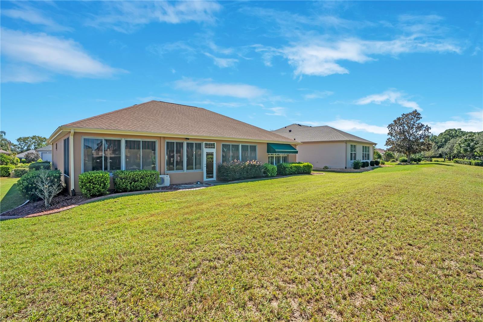 Enjoy a generous backyard with open green space and views of the home's screened enclosure.