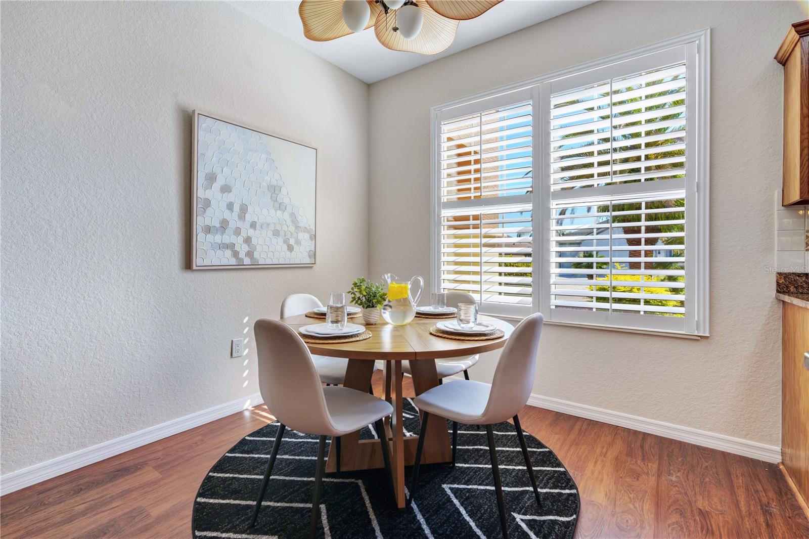Charming dining nook with plantation shutters, abundant natural light, and beautiful wood-look flooring.