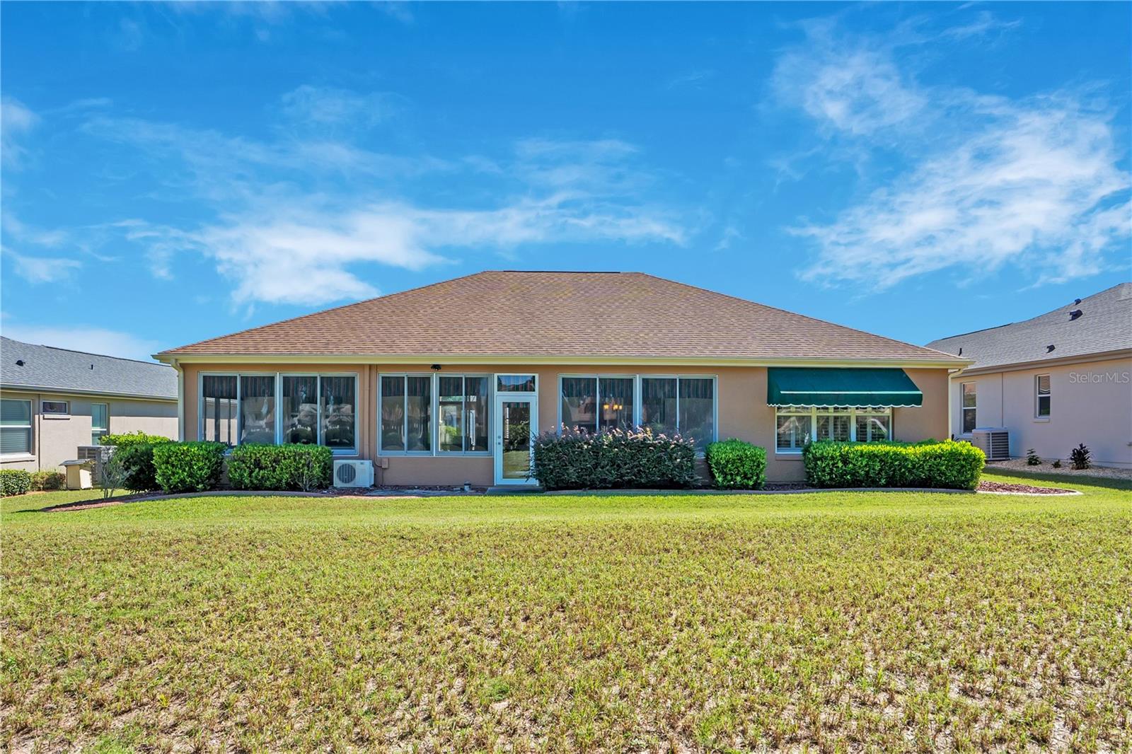 Attractive rear exterior showcasing the home's expansive enclosed lanai and beautifully maintained surroundings.