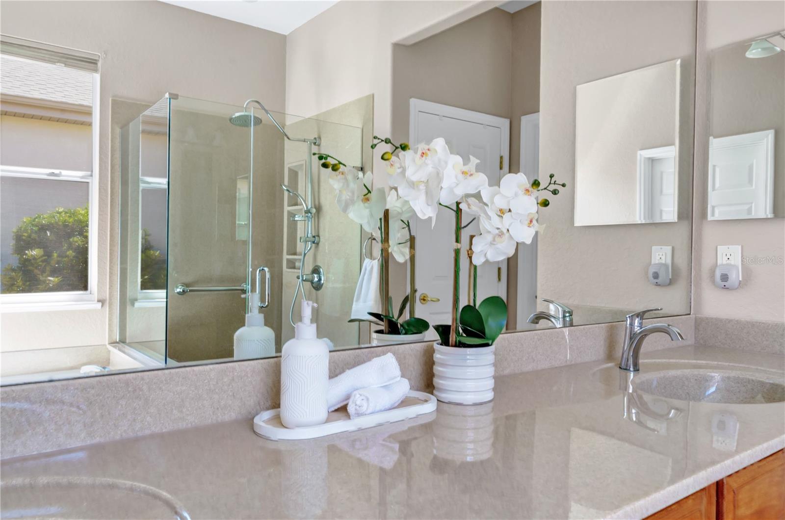 Bright primary bathroom with vanity storage, large mirrors, and a relaxing soaking tub.
