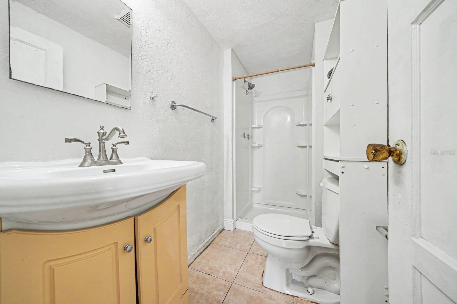 Guest Bath with Yellow Vanity, Shower Enclosure & Ceramic Tile