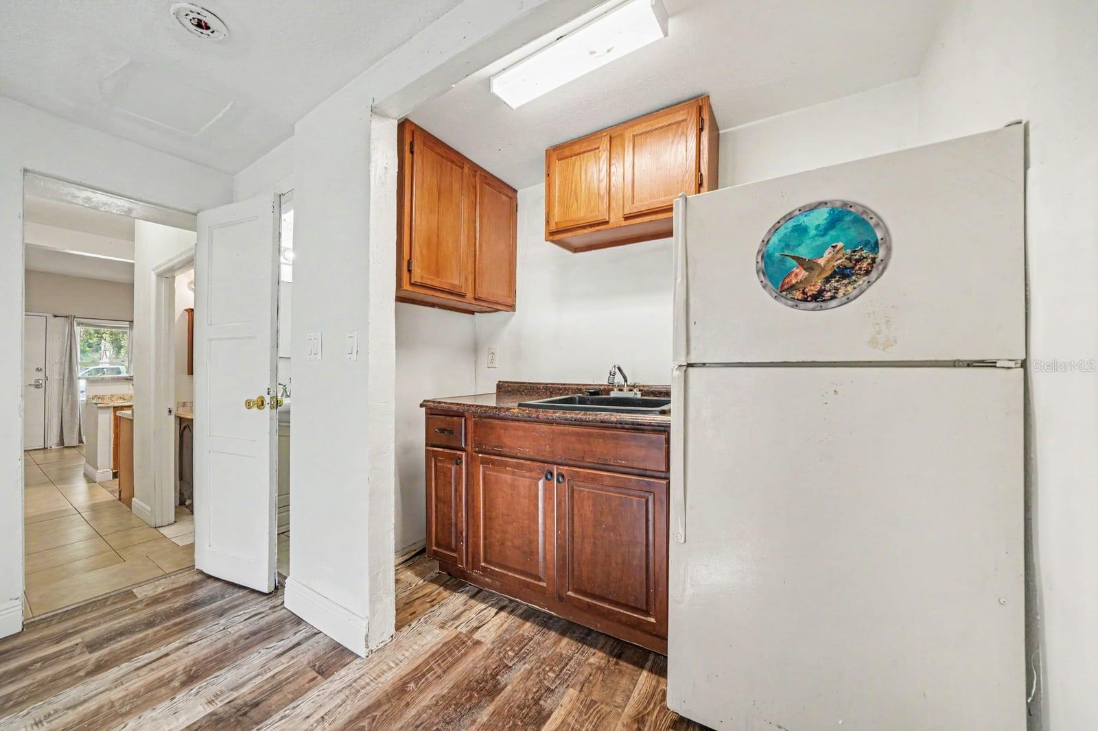 Compact Kitchen with Wood Cabinets, Sink & Access to Main Living Area