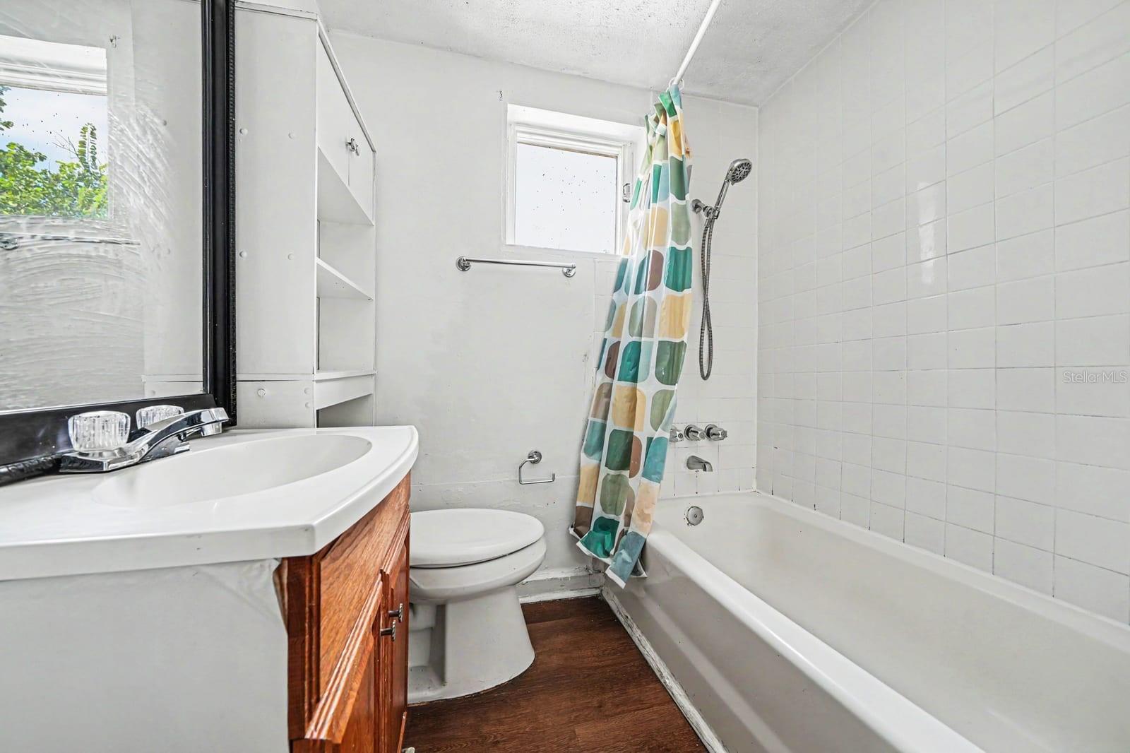 Full Bathroom with Vanity, Toilet, Tub & Shower with Window