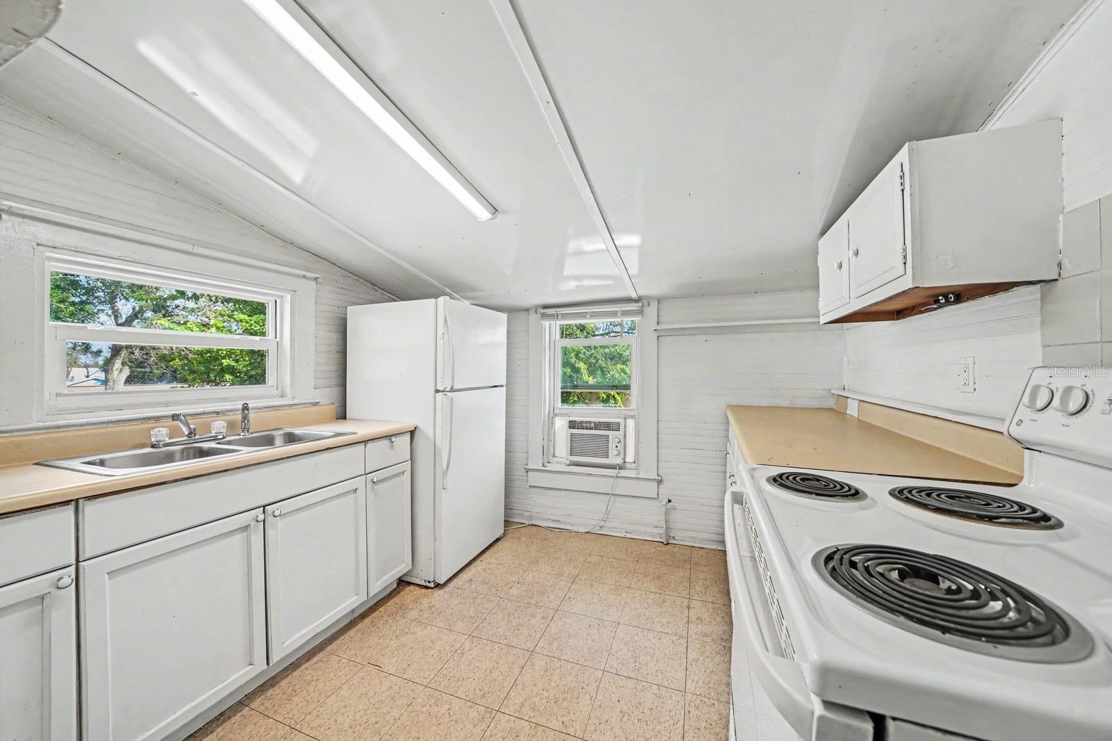 Galley Kitchen with White Appliances, Coil Range & Window Overlooking Trees