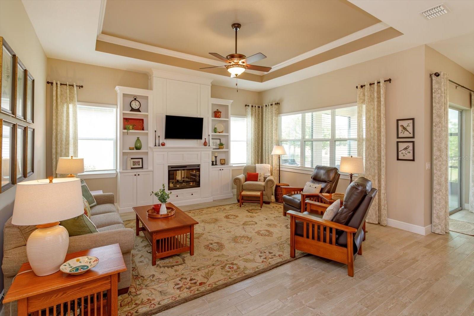 Living Room with Custom Built-in Cabinetry and Electric Fireplace. Designed with hidden storage on both sides of the fireplace and above the TV
