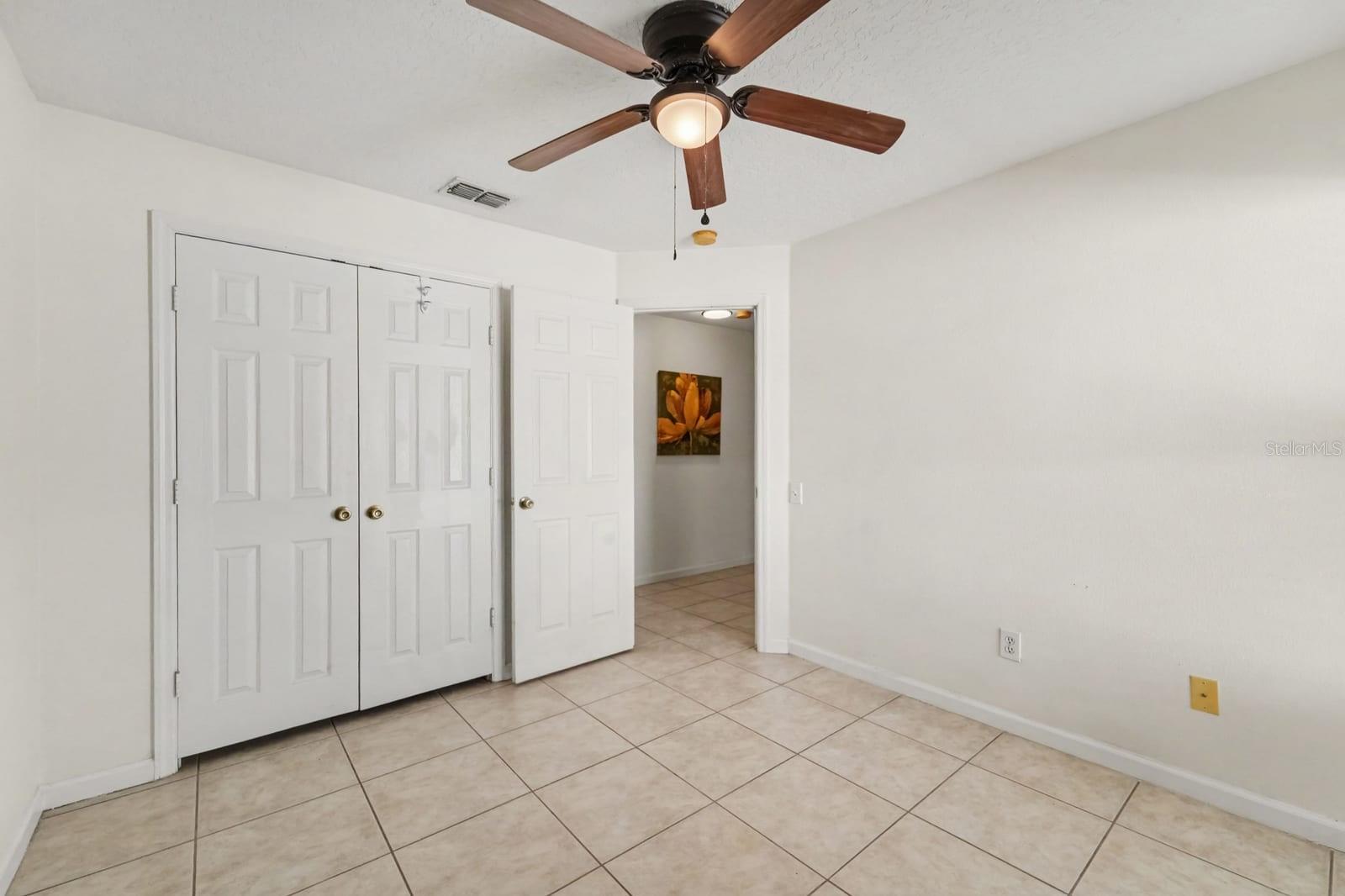 Bright Bedroom with Large Window Overlooking Yard & Ceiling Fan with Light