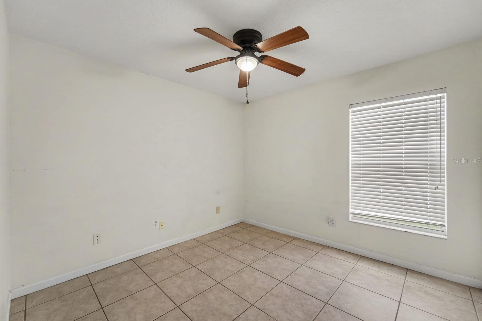 Spacious Bedroom with Ceiling Fan, Large Window & Neutral Color Palette