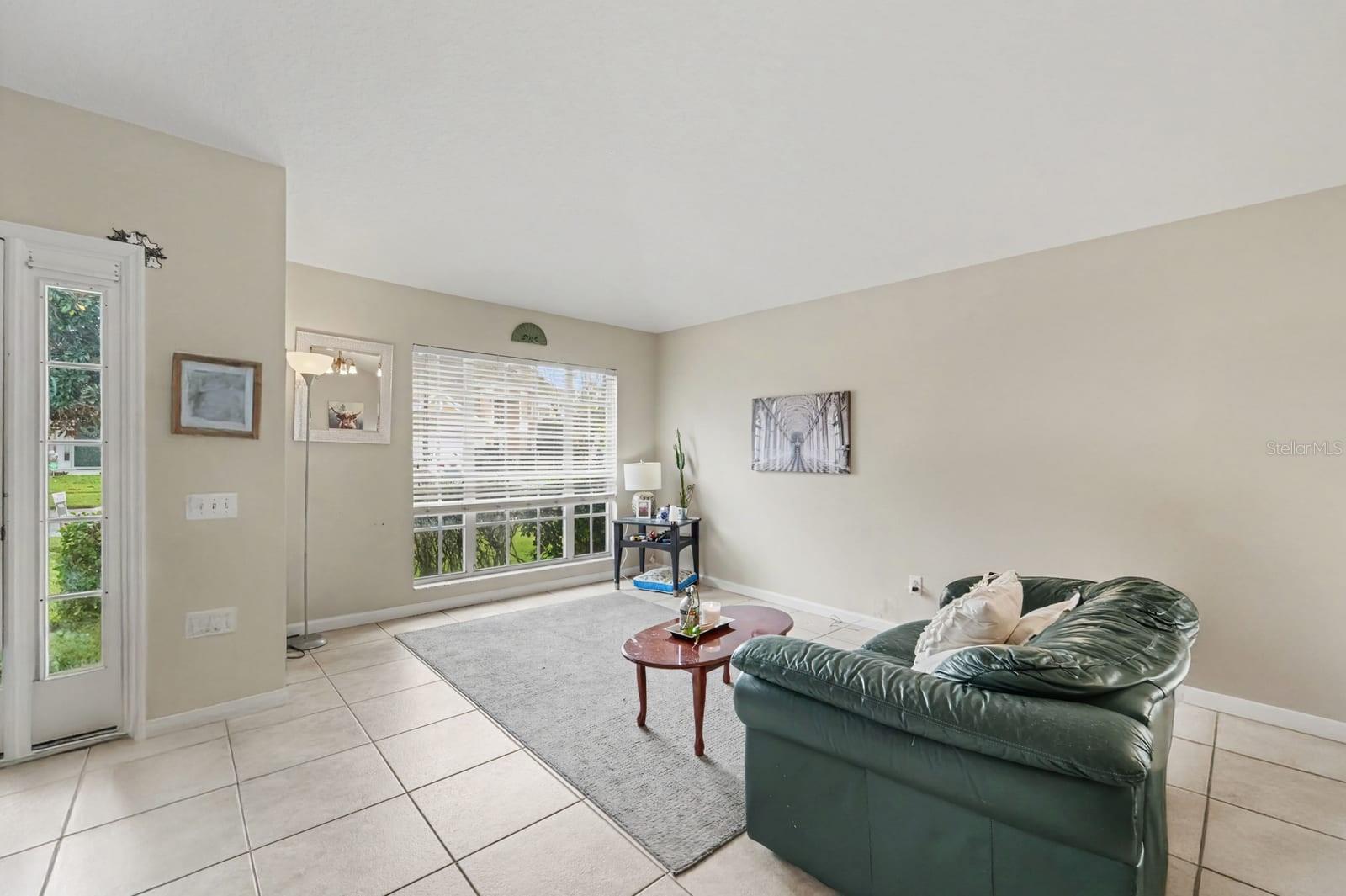 Sunlit Sunroom with Sliding Glass Doors, Tile Flooring & Green Leather Seating