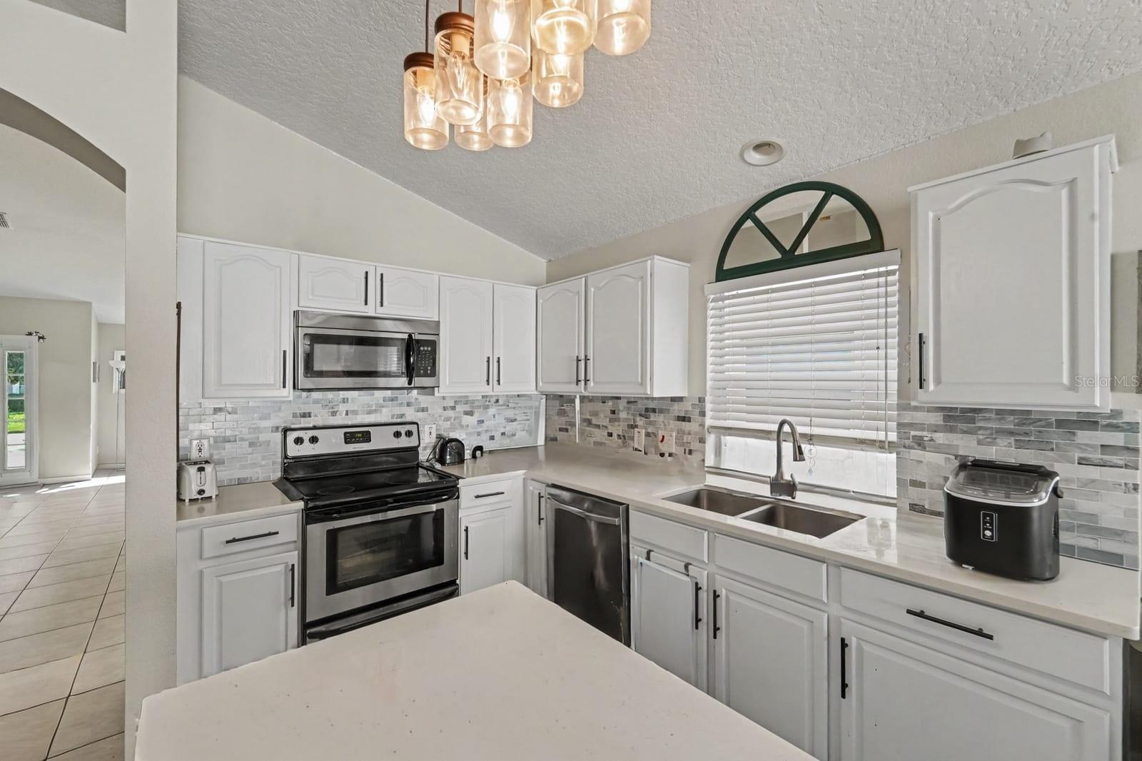 Updated kitchen with white cabinetry, mosaic tile backsplash, and stainless appliances Updated kitchen with white cabinetry, mosaic tile backsplash, and stainless appliances