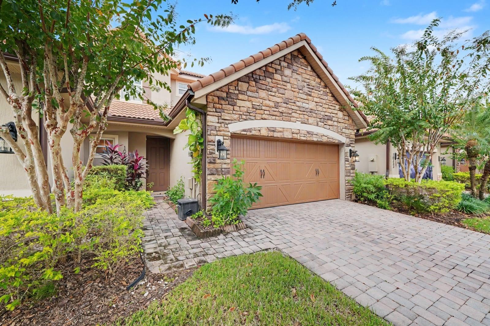Welcoming Stone Facade, Paver Driveway, And Established Grounds