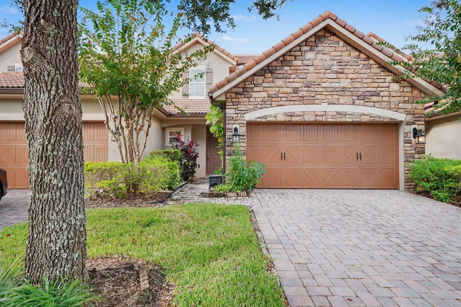 Stone & Stucco Exterior With Mature Landscaping And Two-Car Garage