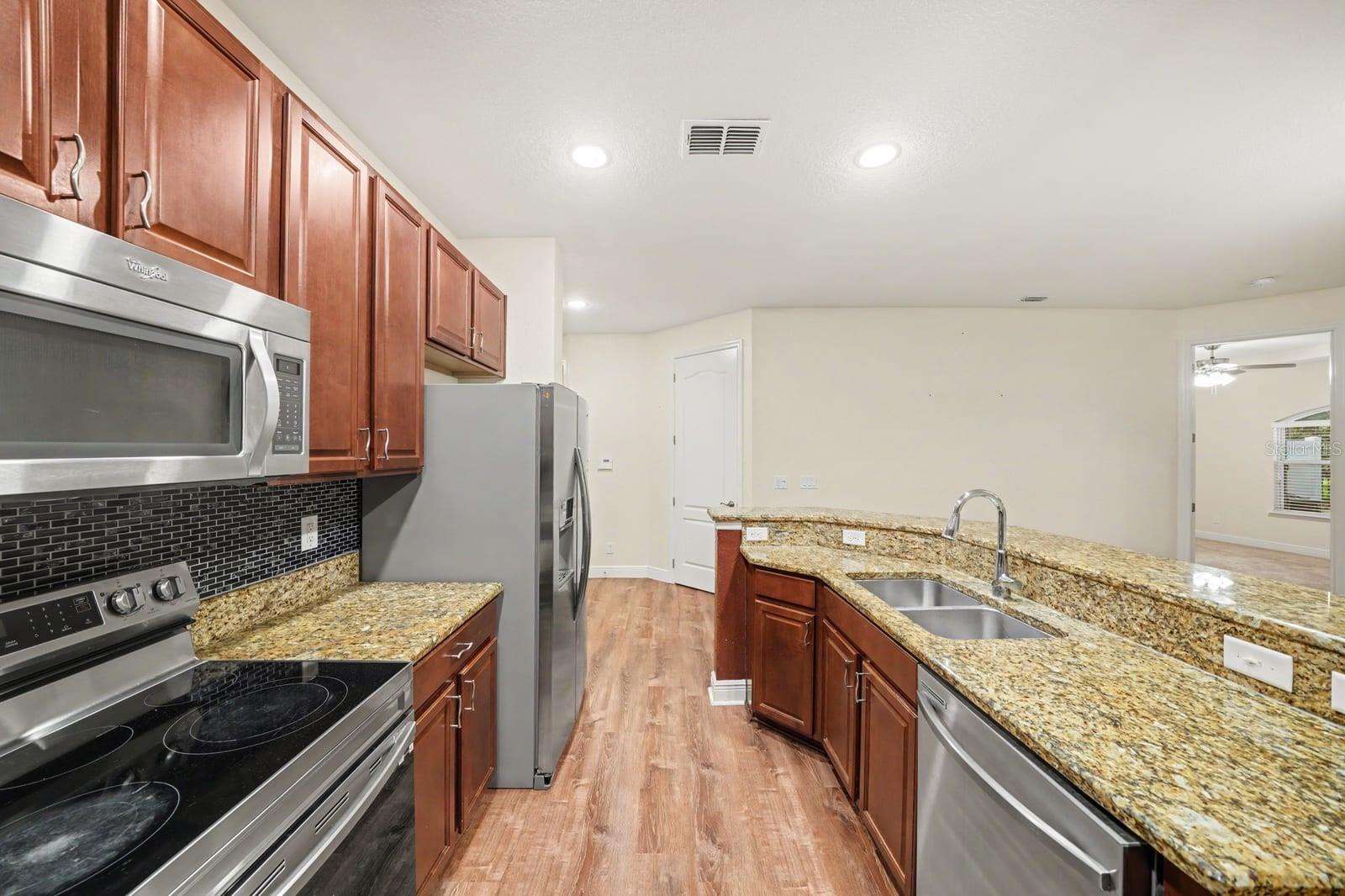 Modern Kitchen Layout With Granite Counters, Double Appliances & Island Sink