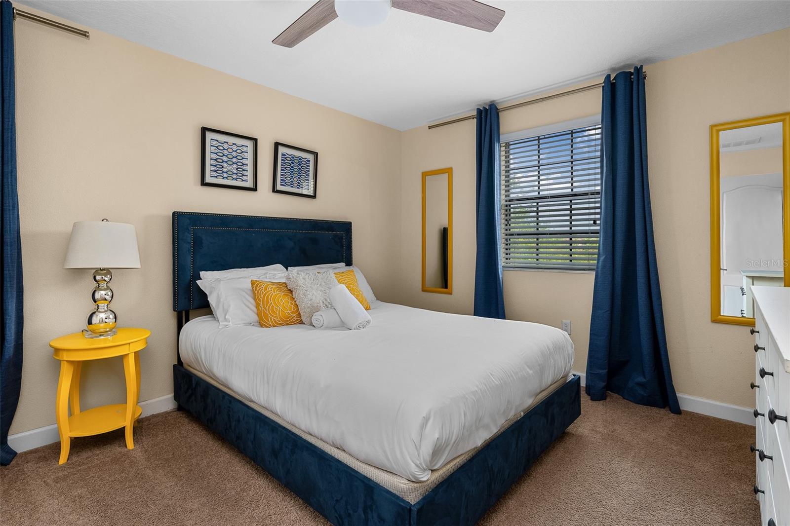 Comfortable Queen Bedroom with Navy and Yellow Accents and Ceiling Fan