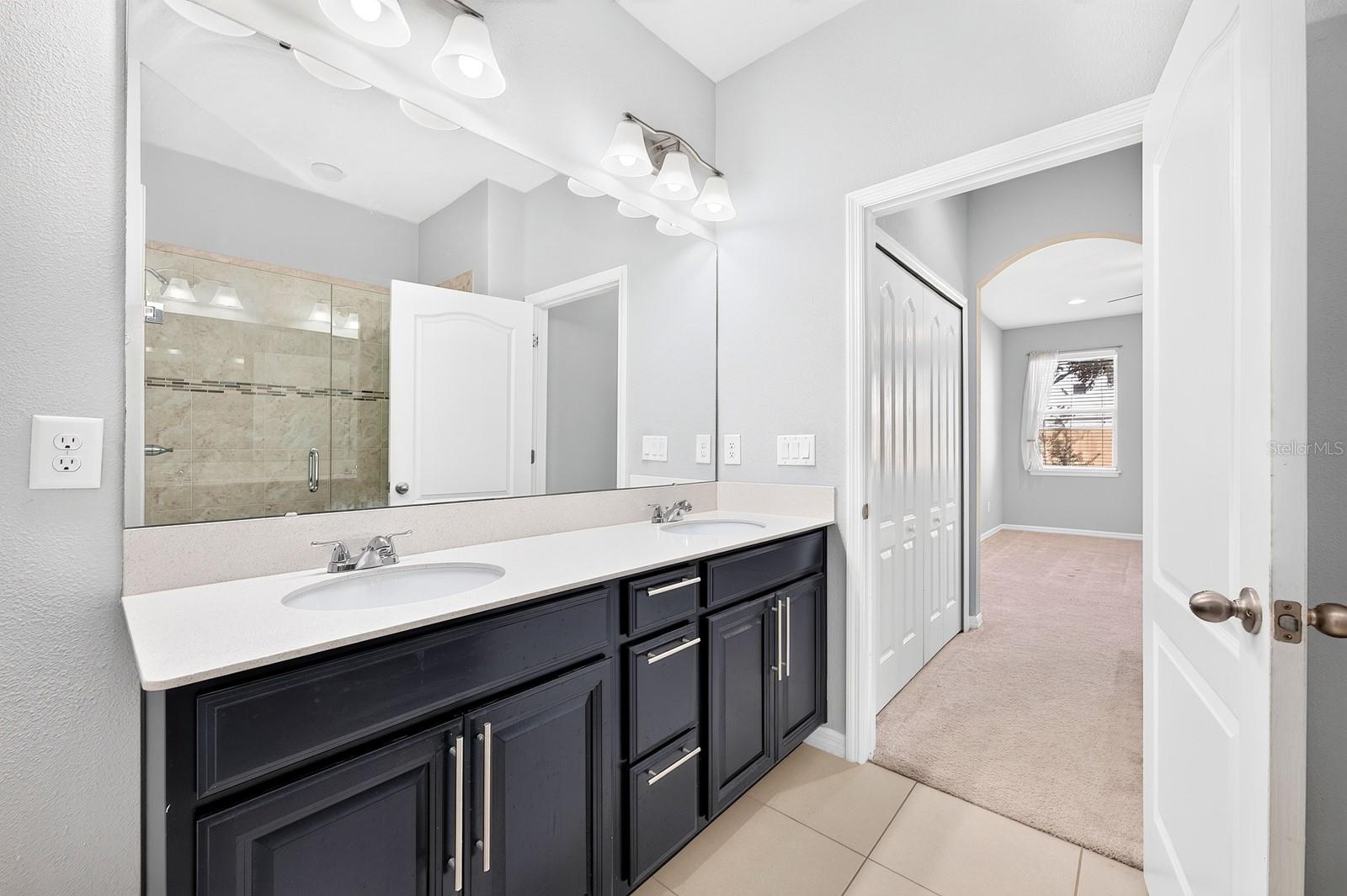 The private Bath features dual sinks, a STEP-IN SHOWER and a linen closet for additional storage.