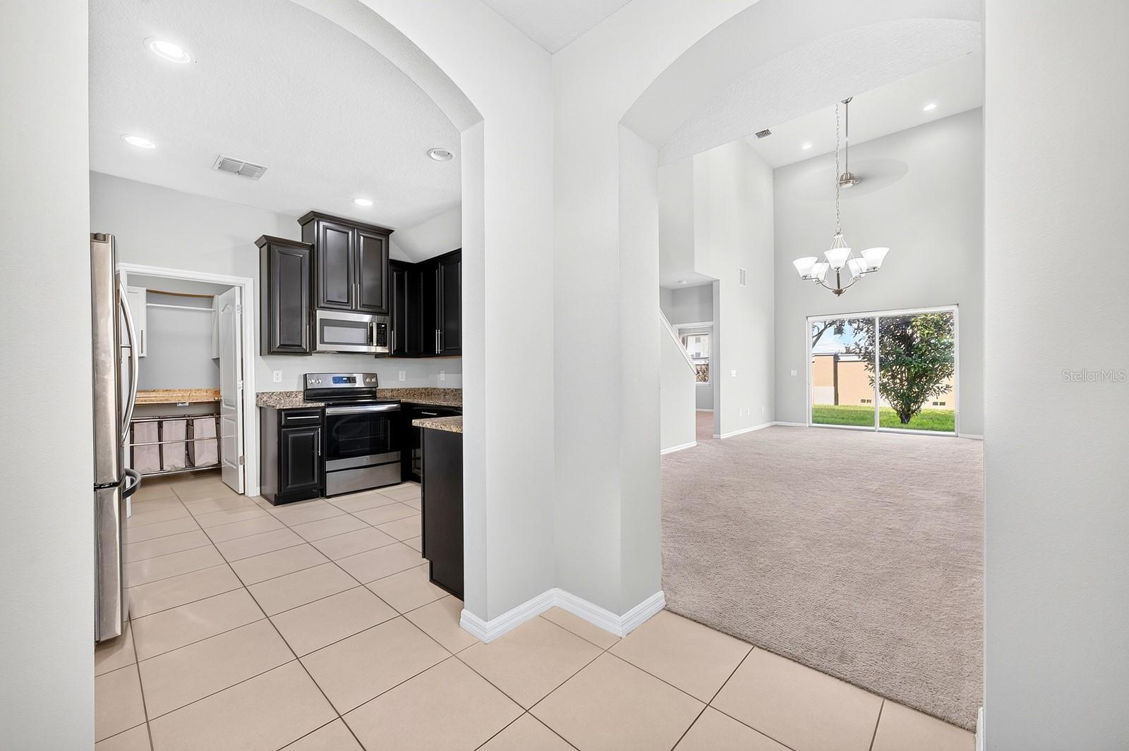 Elegant ARCHED DOORWAYS lead to the Kitchen and the OPEN LIVING and DINING AREA, creating a lovely sense of flow between the main gathering spaces.