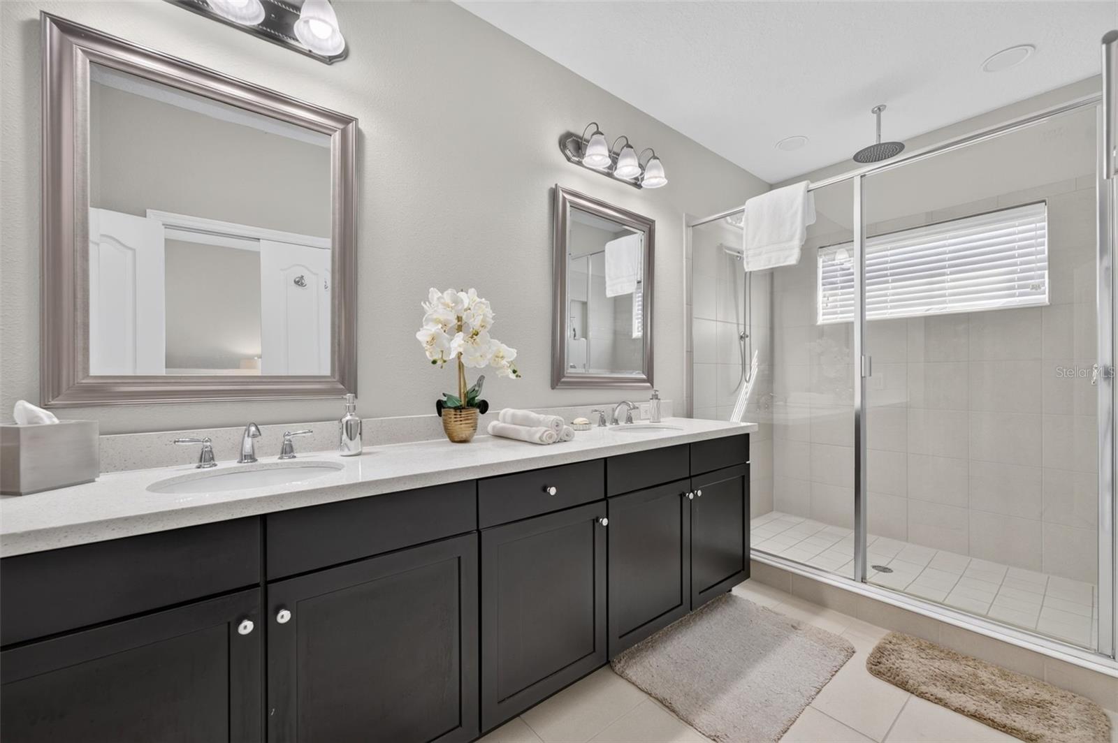 Primary Bathroom features stone counters, tall cabinetry, 2 sinks and an oversized shower