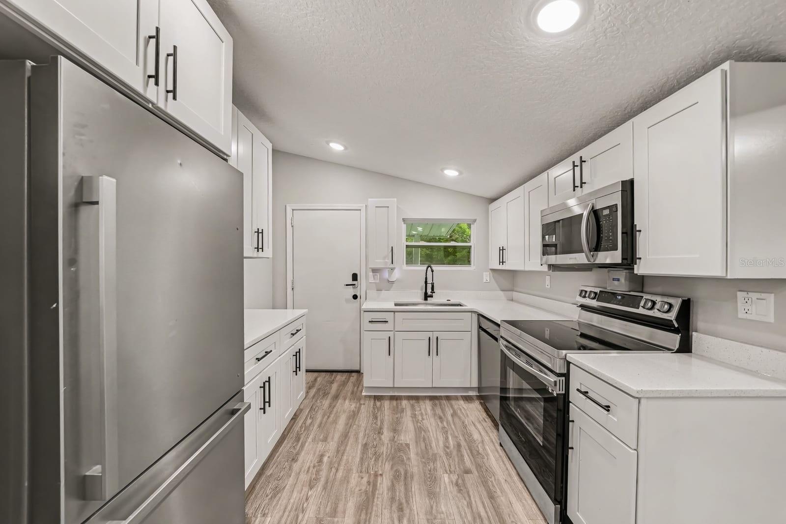 Modern kitchen with white cabinetry, stainless appliances, and open layout