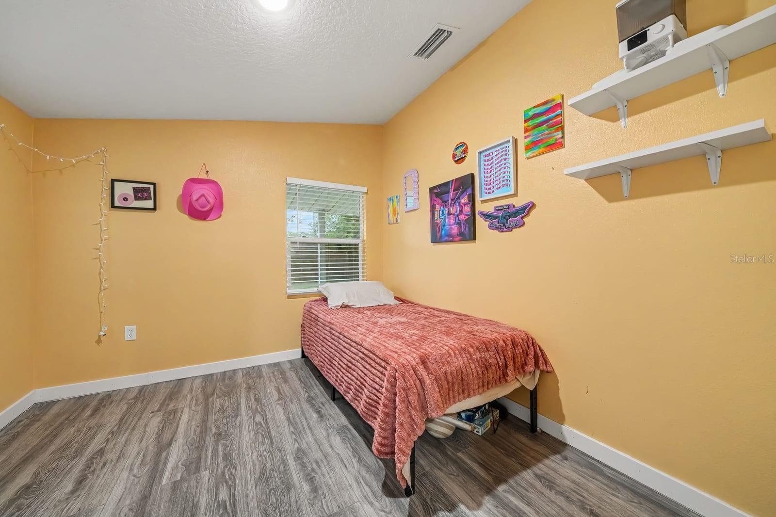 Bright Bedroom with Yellow Walls, Wood Flooring & Large Window