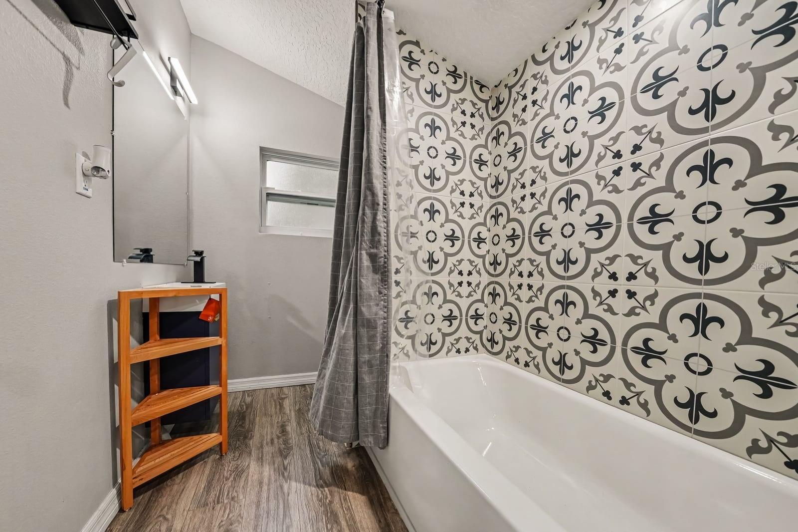Guest Bath Featuring Patterned Tile Accent Wall and Wood Shelving