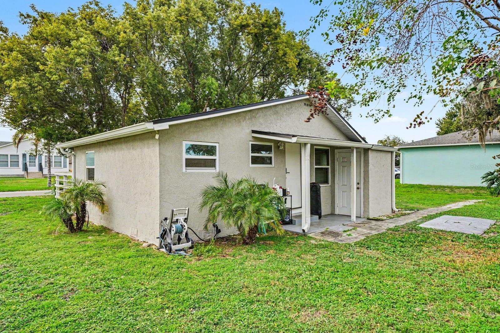 Welcoming entrance features covered porch area and lush tropical plantings