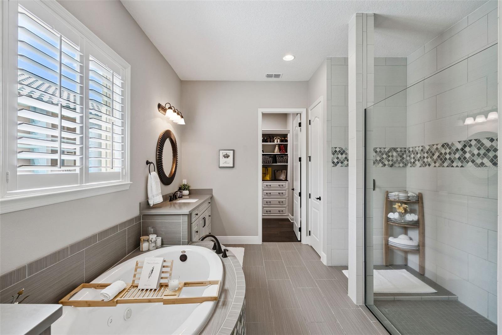 Owners bathroom with dual vanities, a soaking tub, spacious walk-in shower