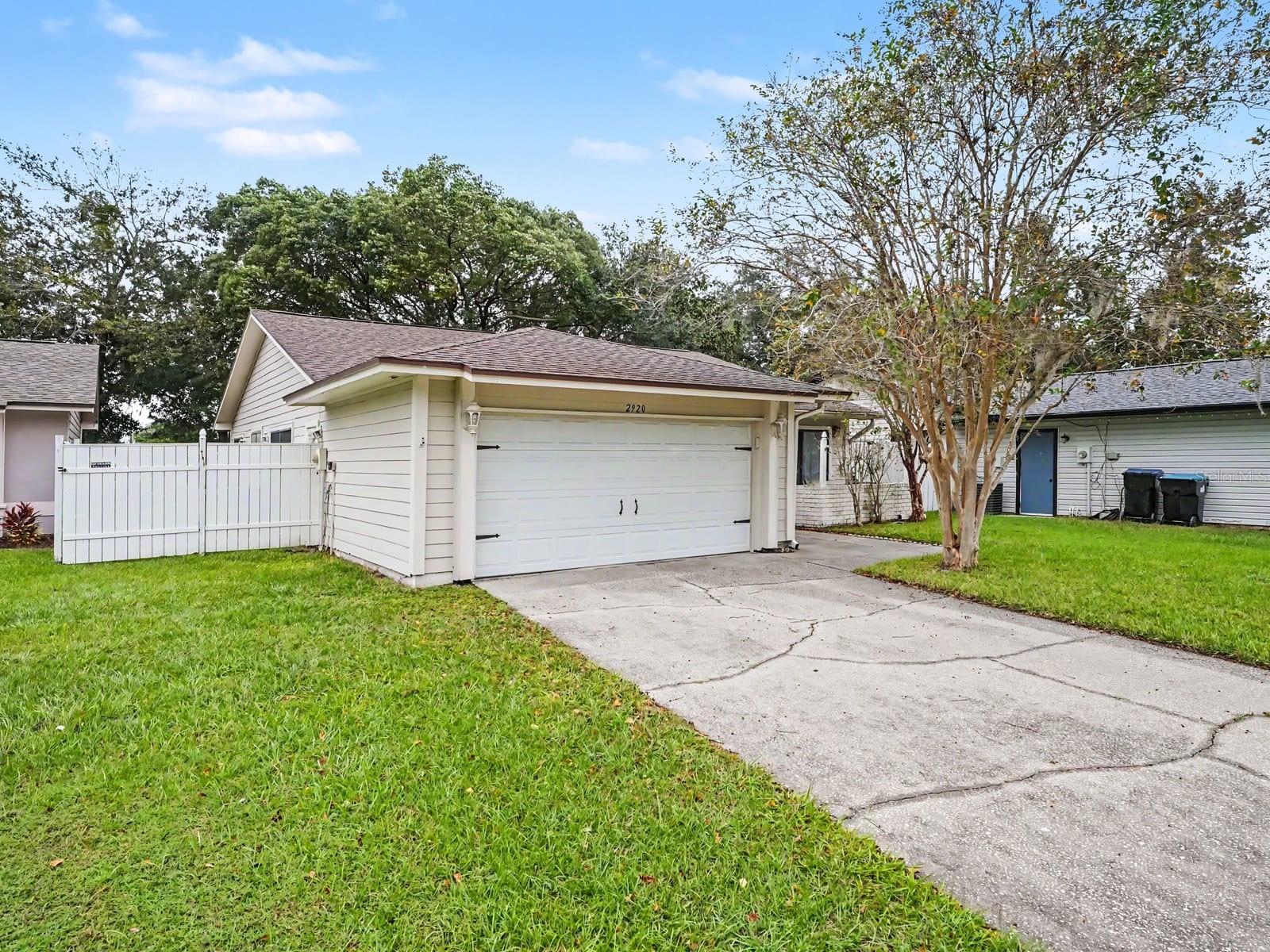 Single-story home with attached garage, white siding & landscaped lawn