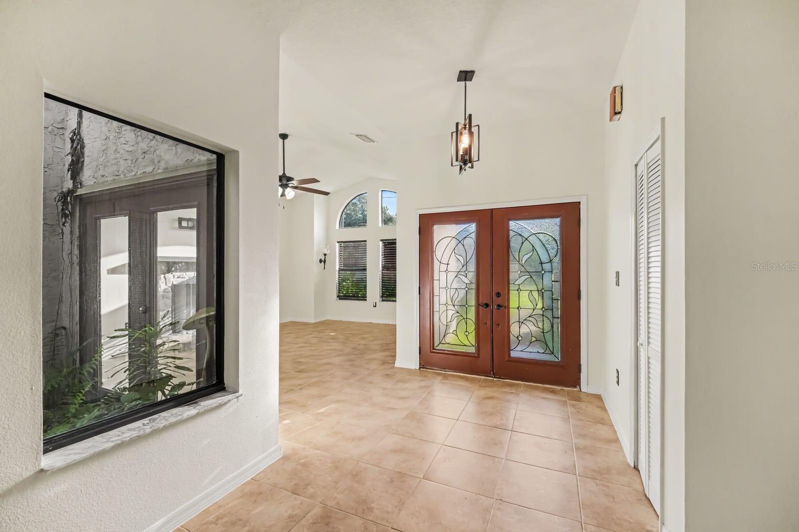 Bright entryway with decorative glass doors and open ceiling layout