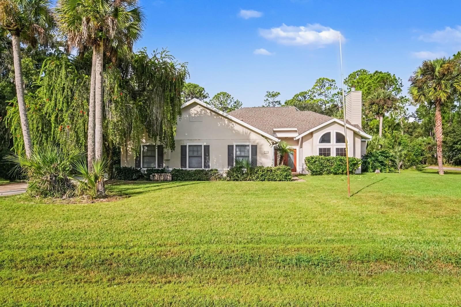 Spacious home on lush grounds with mature palms and manicured lawn