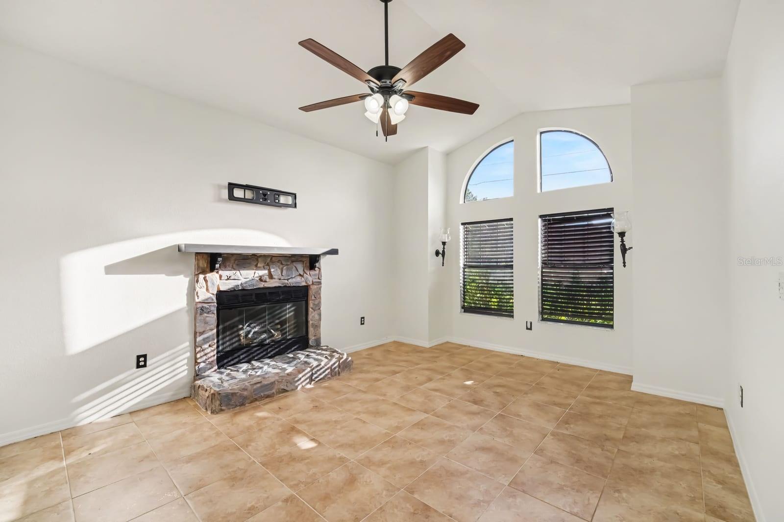 Curved fireplace mantel, large windows, and open floor plan design