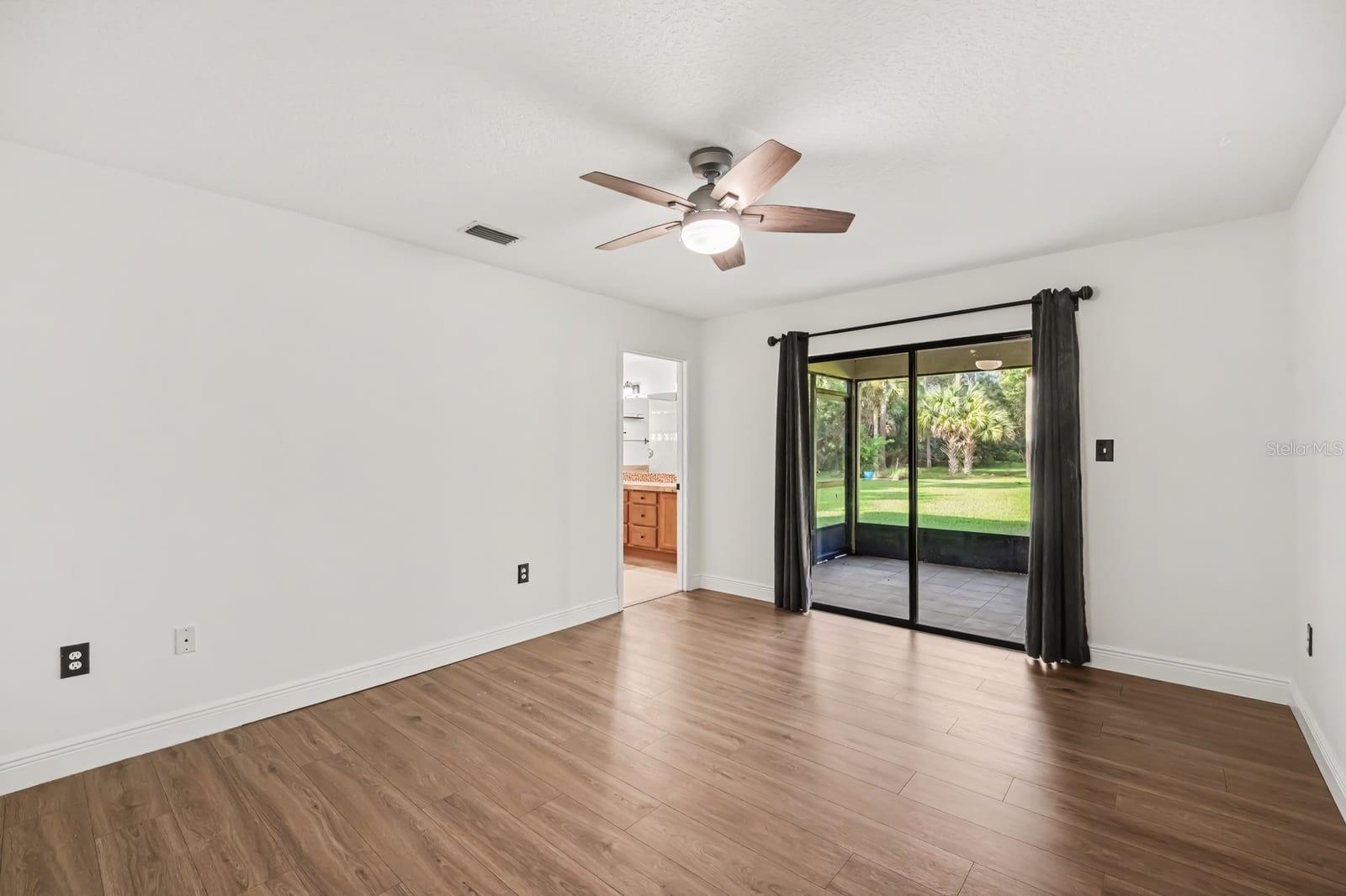 Master Suite With Hardwood Floors, Ceiling Fan & Sliding Glass Door To Patio