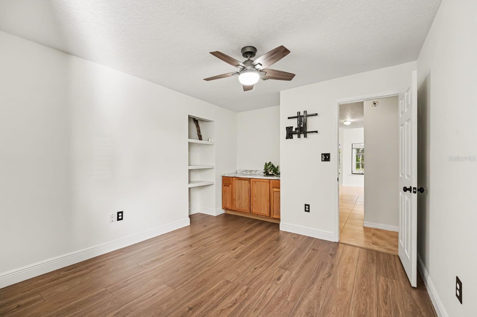 Secondary Bedroom with Ceiling Fan, Built-In Shelving, and Wood Flooring